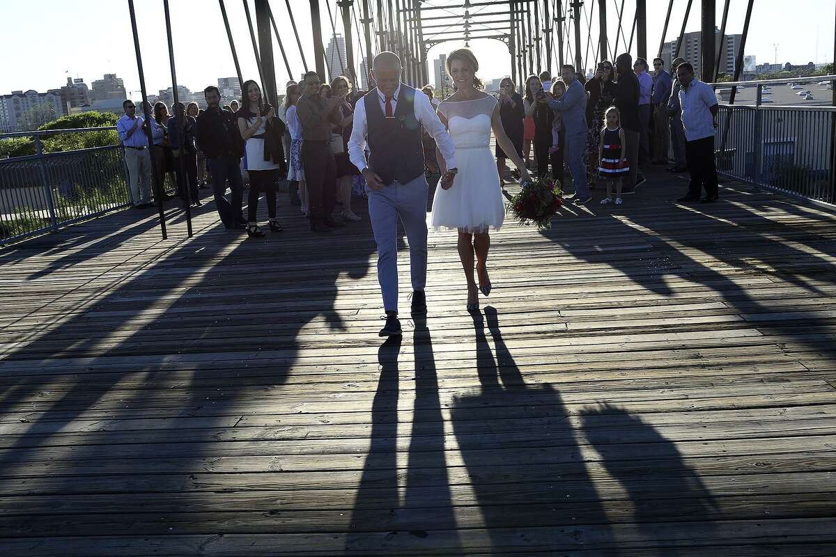 Devin Verdon and Suzie Verdon walk toward Dignowity Hill after their wedding ceremony on the Hays Street Bridge April 2, 2016.