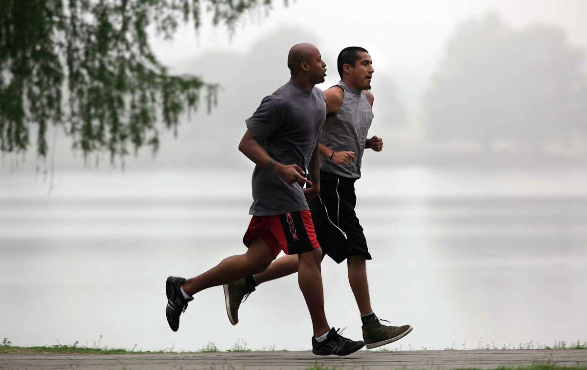Two runners take to the fog as they run laps around Woodlawn Lake.