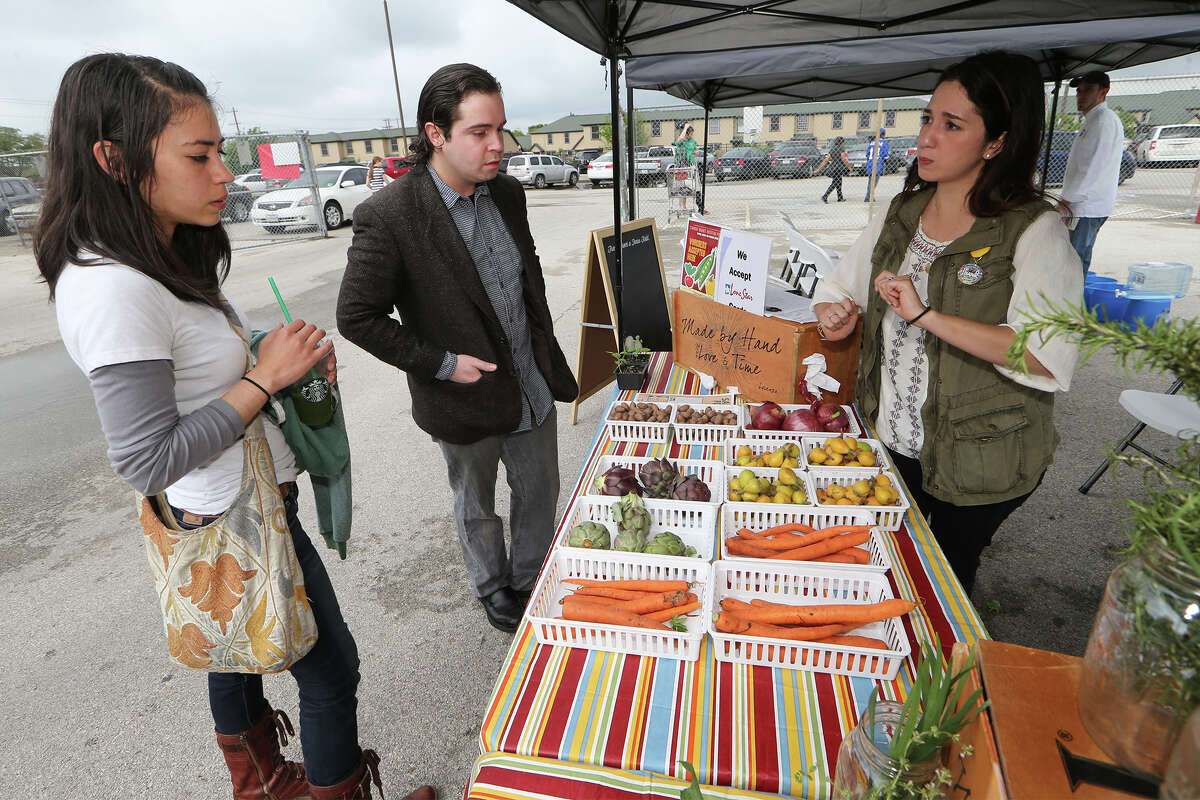 Monica Juarez (left) and Mauricio Gomez looks over fresh fruits and vegetables offered by Kristin Cuellar of the San Antonio Food Bank during the Sam Houston High School farmers market at the school on April 18, 2015.