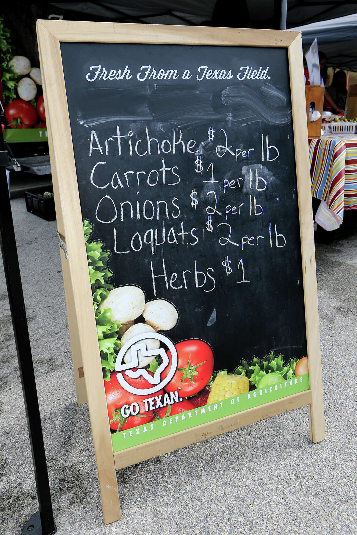 A sign advertises fruits, vegetables and herbs during the Sam Houston High School farmers market at the school on April 18, 2015.