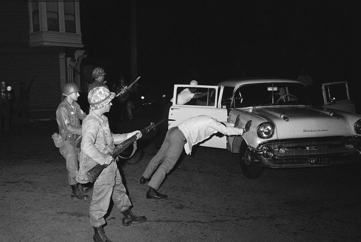 FILE - Two black occupants of this car are held at bay by California National Guardsmen with fixed bayonets in the Hunters Point riot area of San Francisco, Sept. 28, 1966. The car was stopped when it was suspected of carrying guns and ammunition. The area was secured by Guardsmen who imposed curfew. (AP Photo/Robert H. Houston)