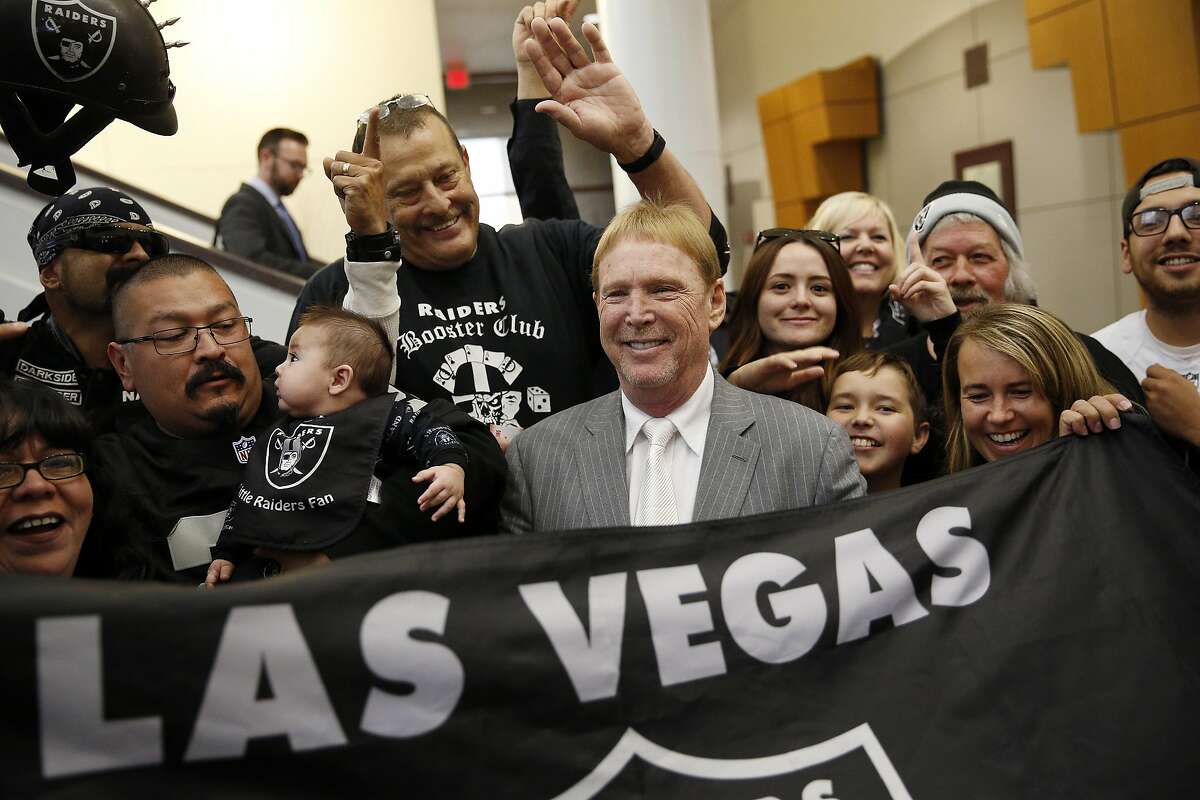 FILE - In this April 28, 2016 file photo, Oakland Raiders owner Mark Davis, center, meets with Raiders fans after speaking at a meeting of the Southern Nevada Tourism Infrastructure Committee in Las Vegas. Proponents of an NFL football stadium in Las Vegas aren't budging on their request for $750 million in hotel tax dollars and don't want to return any profits to the public. An oversight committee could finalize a recommendation for the Legislature next week. (AP Photo/John Locher, File)
