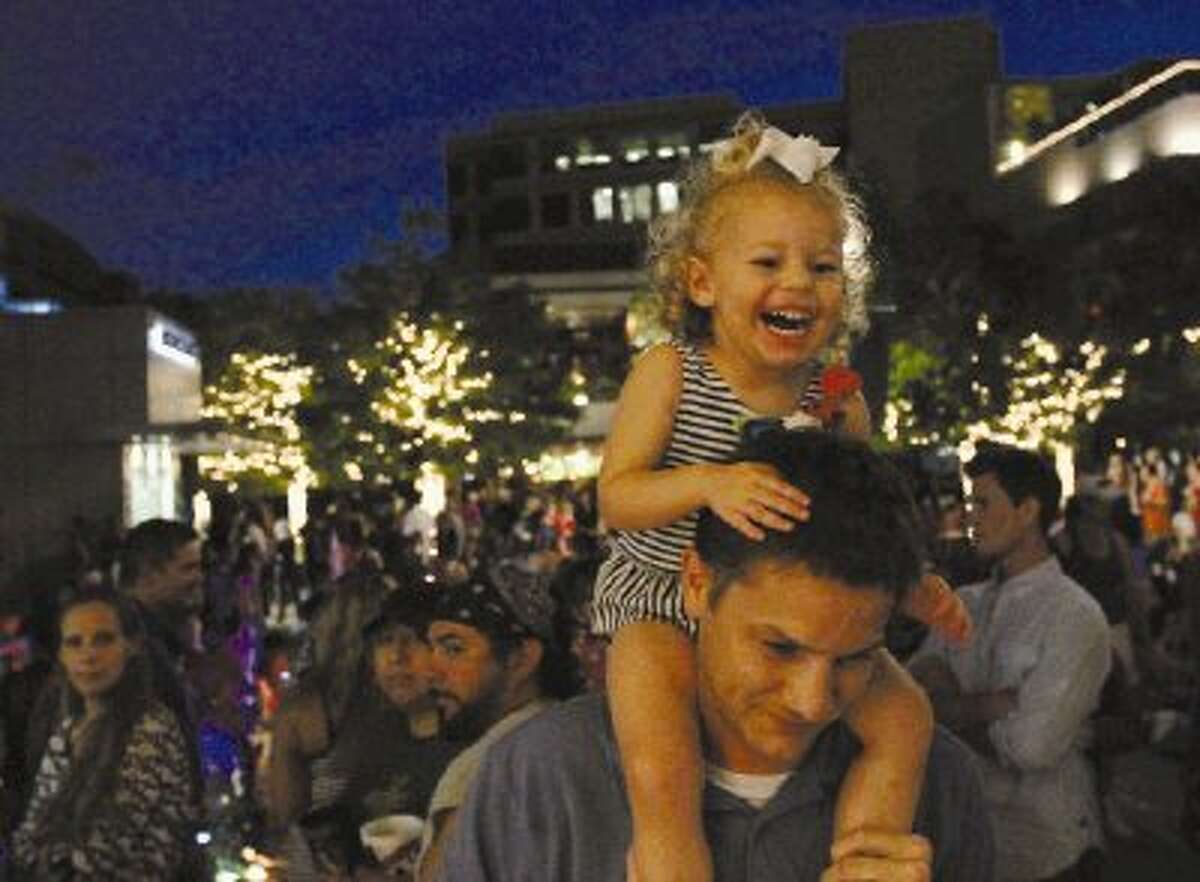 Kimley Cole, 2, laughs as music is played while her dad, Justin, holds her up so she can see the band during a Memorial Day celebration at The Woodlands Waterway on Sunday. Go to HCNPics.com to view and purchase this photo, and others like it.