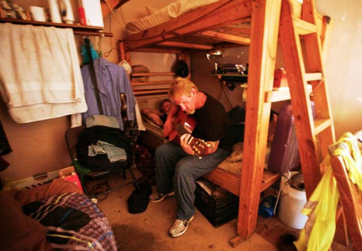 A resident of Bonnie’s House plays his guitar at his bunk. Everything he owns is in that corner.