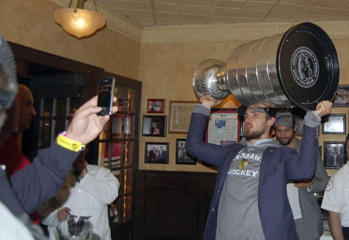 The Chicago Blackhawks’ Niklas Hjalmarsson hoists the Stanley Cup for fans inside Harry Caray’s on Tuesday morning in Rosemont, Ill.