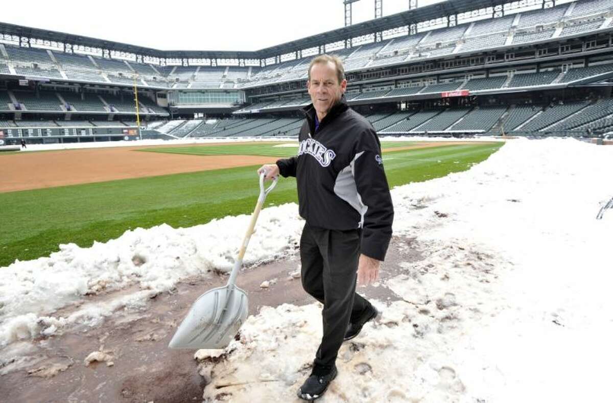 Colorado Rockies owner Dick Monfort shovels snow from the field before the start of a scheduled doubleheader between the New York Mets and the Colorado Rockies on Tuesday in Denver.