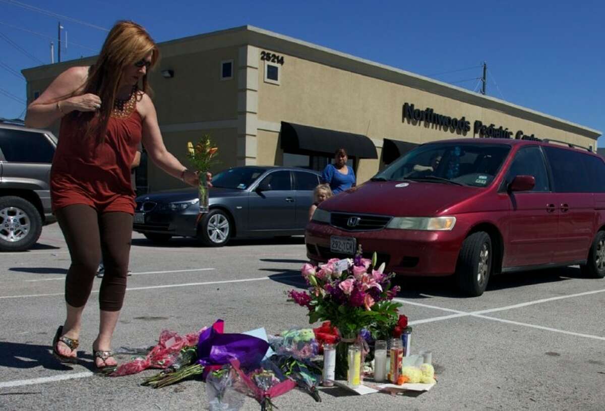 Geanette Smith, of Conroe, places flowers at a makeshift memorial for murder victim Kala Golden, 28, in the parking lot of the Northwoods Pediatric Center where Golden was gunned down Wednesday in The Woodlands.