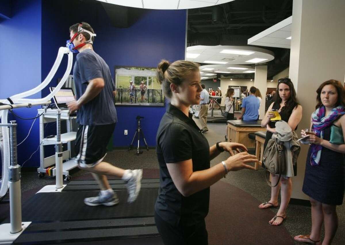 A runner demonstrates the use of some of the specialized equipment available at the Memorial Hermann Ironman Sports Medicine Institute in The Woodlands, as Exercise Physiologist Allison Shepherd, center, explains to visitors the benefits of such equipment.