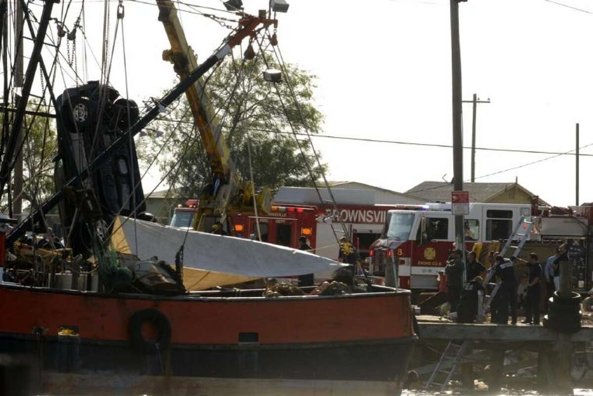 A vehicle is lifted from the water by a crane at the Shrimp Basin located at the Port of Brownsville Thursday. Five people died when the sport utility vehicle in which they were riding plunged into a South Texas port basin.