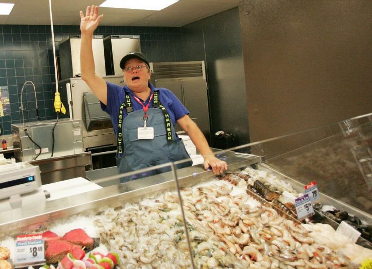 Kroger employee Debra Hulsey waves to customers from the seafood section during the grand opening celebration for the Kroger Marketplace in Willis.