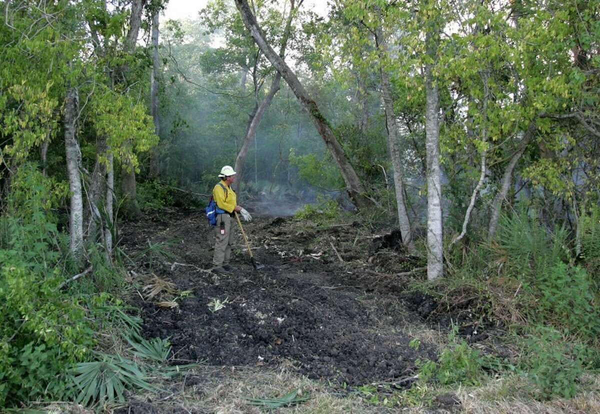 A Texas Forest Service firefighter surveys a fire line Saturday near the scene of a large mulch yard fire on Highway 242 East in Conroe.