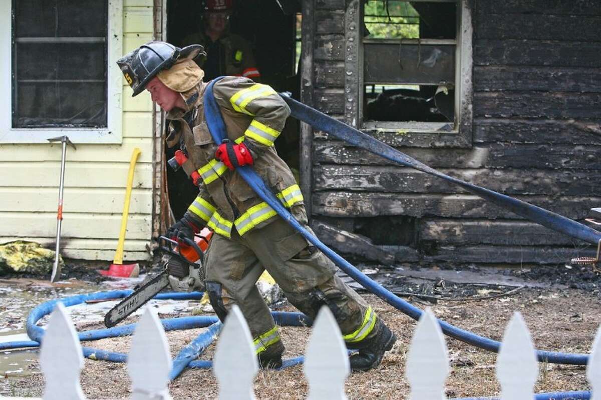A firefighter walks in front of an East County home on Springfield Drive that caught fire after it was struck by lightning.