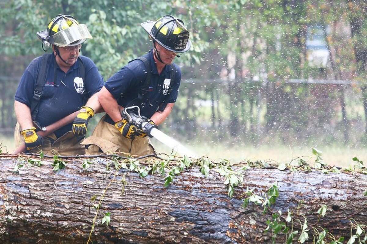 Firefighters dowse a smoldering tree they cut down after a lightning strike caused a fire at a home on Springfield Drive in East County Sunday.