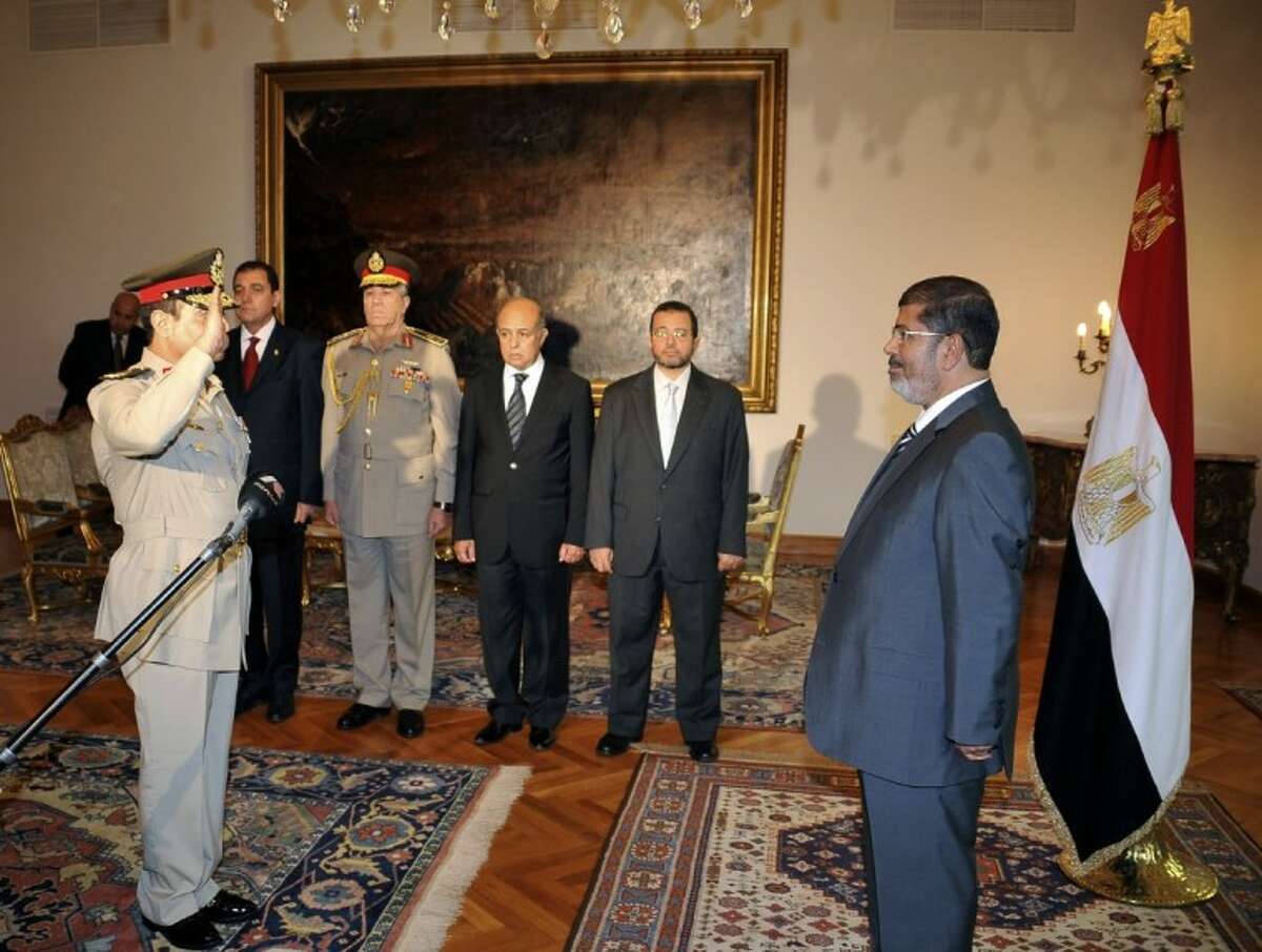 Egyptian President Mohammed Morsi, right, swears in newly-appointed Minister of Defense, Lt. Gen. Abdel-Fattah el-Sissi, left, in Cairo, Egypt, Sunday. Egypt's Islamist president ordered his former defense minister and chief of staff to retire on Sunday and canceled the military-declared constitutional amendments that gave top generals wide powers.