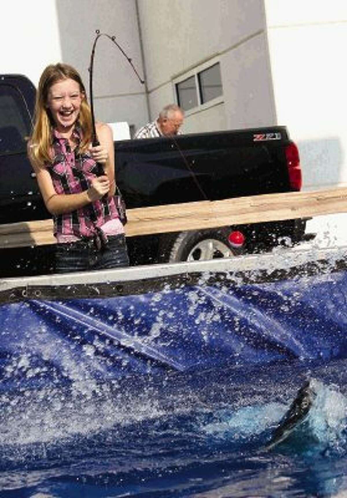 Brittany Buttler catches a catfish at the “Hooked on Chevy” event at Buckalew Chevrolet in Conroe Saturday. Children fished for catfish and earned T-shirts and tackle boxes for the number of fish they caught. Go to HCNPics.com to view and purchase this photo and others like it.