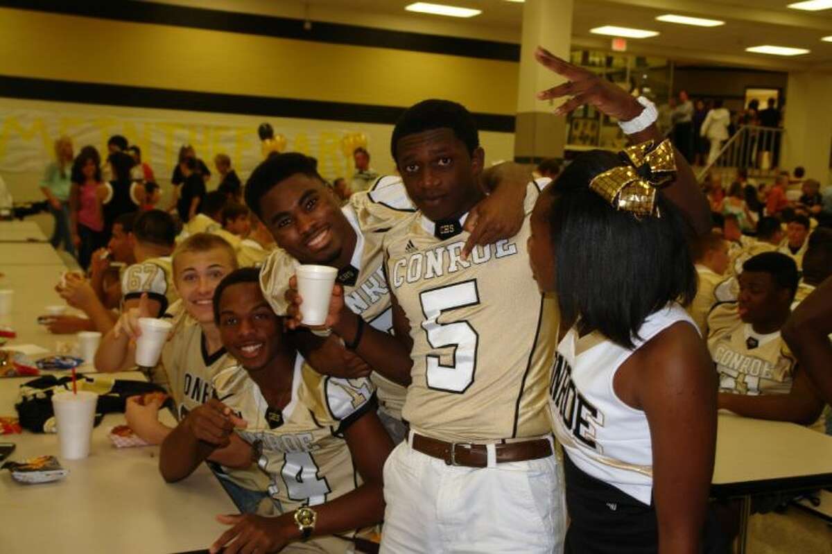 Conroe football players Stedman Bell, Darius Nelms and Auther Harris (5) ham it up during “Meet The Tigers” with cheerleader Klarc Marshall on Monday night.`