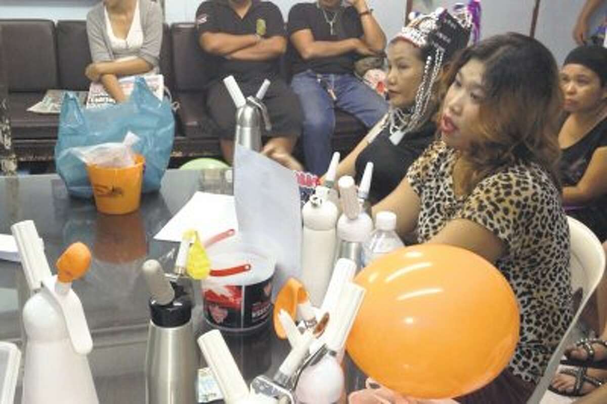 Thai vendors are shown at a police news conference with laughing gas balloons, foreground, following their arrest in Bangkok, Thailand on August 24. Thai authorities are cracking down on vendors in Bangkok's main backpacker district selling cheap doses of balloons filled with nitrous oxide, or laughing gas, to tourists.