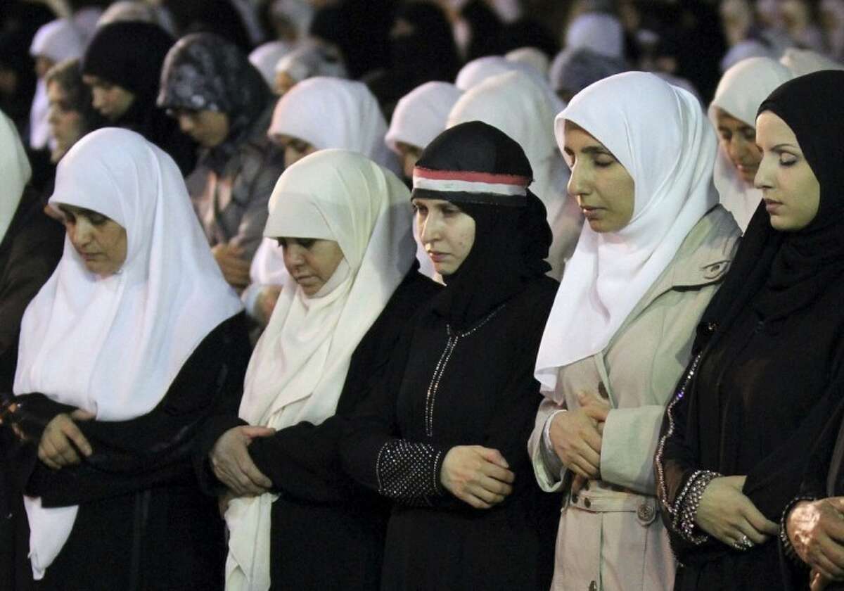 Syrian women, who live in Amman, Jordan, perform Ramadan special prayers before a rally calling for President Bashar Assad to step down, in Amman, Jordan, Friday, Aug. 26, 2011. Woman at centre bears a Syrian flag upon her head scarf. (AP Photo/ Nader Daoud)