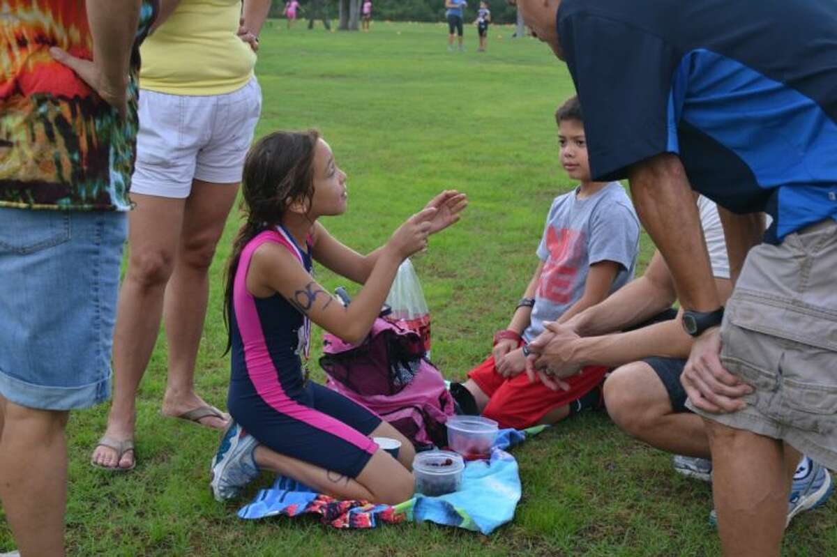 Daisy de Carlos, 9, of Sweeney, came in second place for her age group. After she finished the race, her father and uncle asked her questions concerning her pace and endurance during the race and she is telling them that she passed up everyone and no one passed her.
