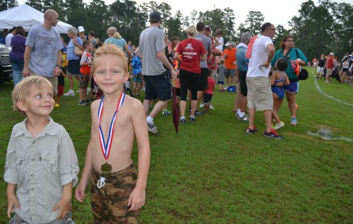 Matthew Smith, 7, of Oak Ridge North, shows his finishing medal as little brother, Andrew, 4, looks up to him at Saturday’s 2013 Kiwanis YMCA Kids Triathlon at South Montgomery County YMCA.