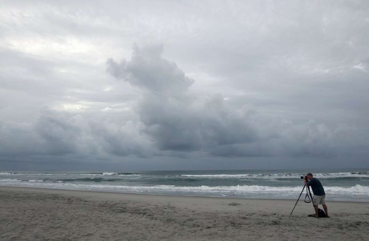 Cash Haggarty, of Washington, takes photos of the sunrise in Atlantic Beach, N.C. on Thursday. A hurricane watch was issued early Thursday for much of the North Carolina coast. Officials along the East Coast of the United States are calculating what they need to do if Irene becomes the first major hurricane to strike the region in seven years. (AP Photo/Chuck Burton)