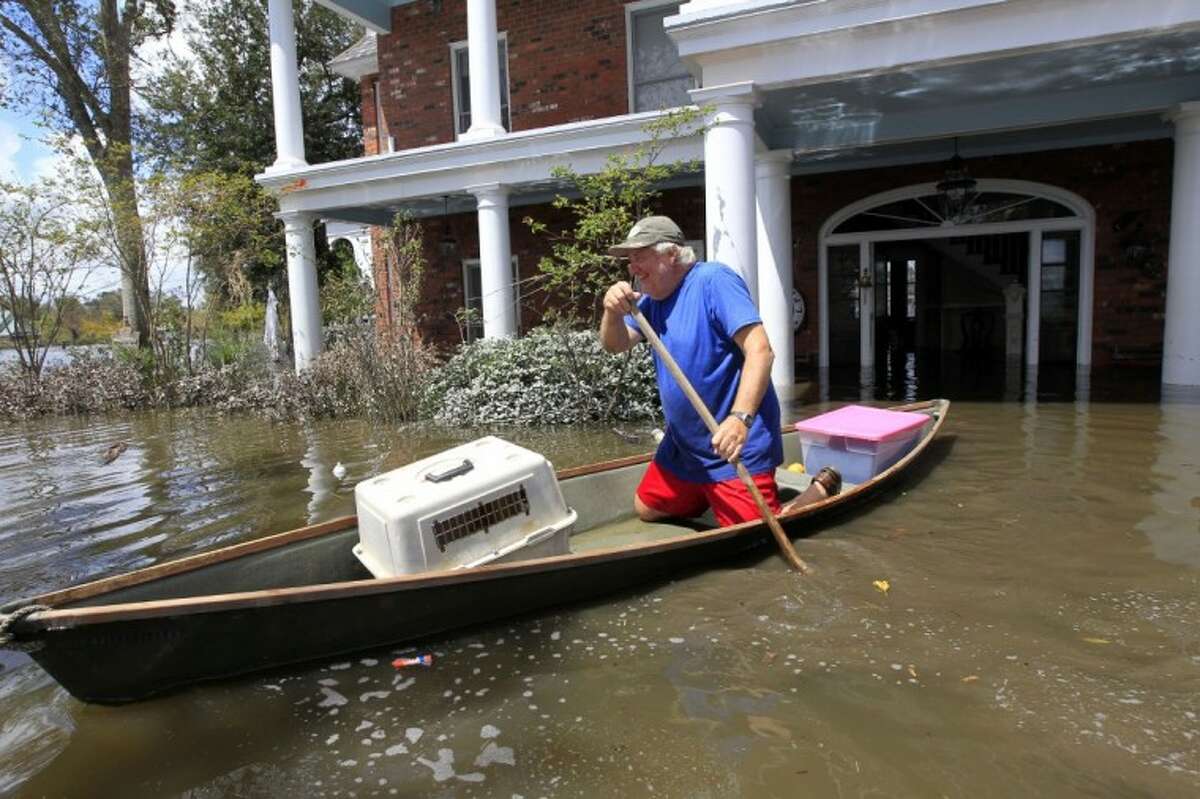 Don Duplantier paddles a pirogue from his flooded home as floodwaters from Hurricane Isaac recede in Braithwaite, La. Sunday. Duplantier had retrieved his cat and had collected his daughter's bridesmaid dress for the upcoming wedding of his son.