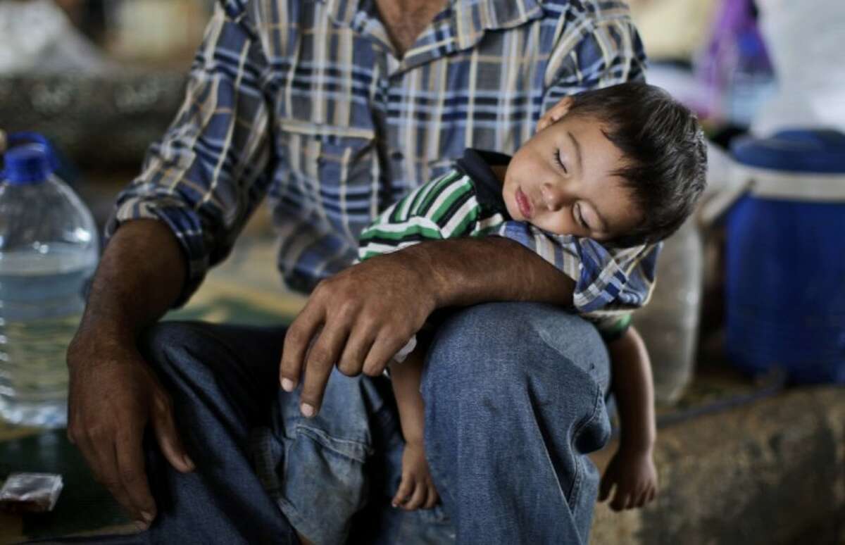 Syrian, Ghassan Khalil, 30, who fled his home in Marea 12 days ago due to Syrian government shelling of his house, holds his sleeping son Mahmoud, 2, who suffers from fever, as they take refuge at the Bab Al-Salameh border crossing in hopes of entering one of the refugee camps in Turkey, near the Syrian town of Azaz, Monday.