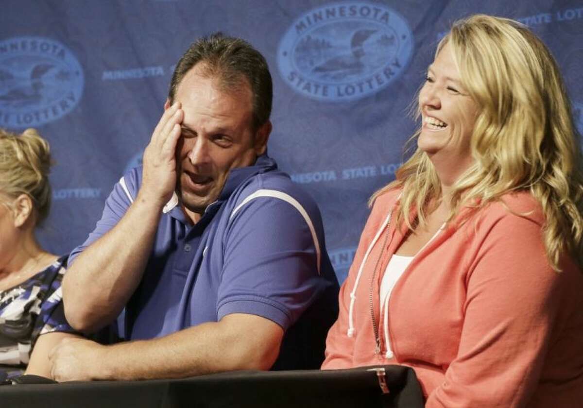 Paul White, of Ham Lake, Minn., gets a laugh from his girlfriend Kim VanReese, right, as he talks about his plans after he was announced one of the winners of the $448.4 million Powerball Jackpot Thursday in Minneapolis. White’s share of the jackpot is $149.4 million. The woman at left is a co-worker friend.