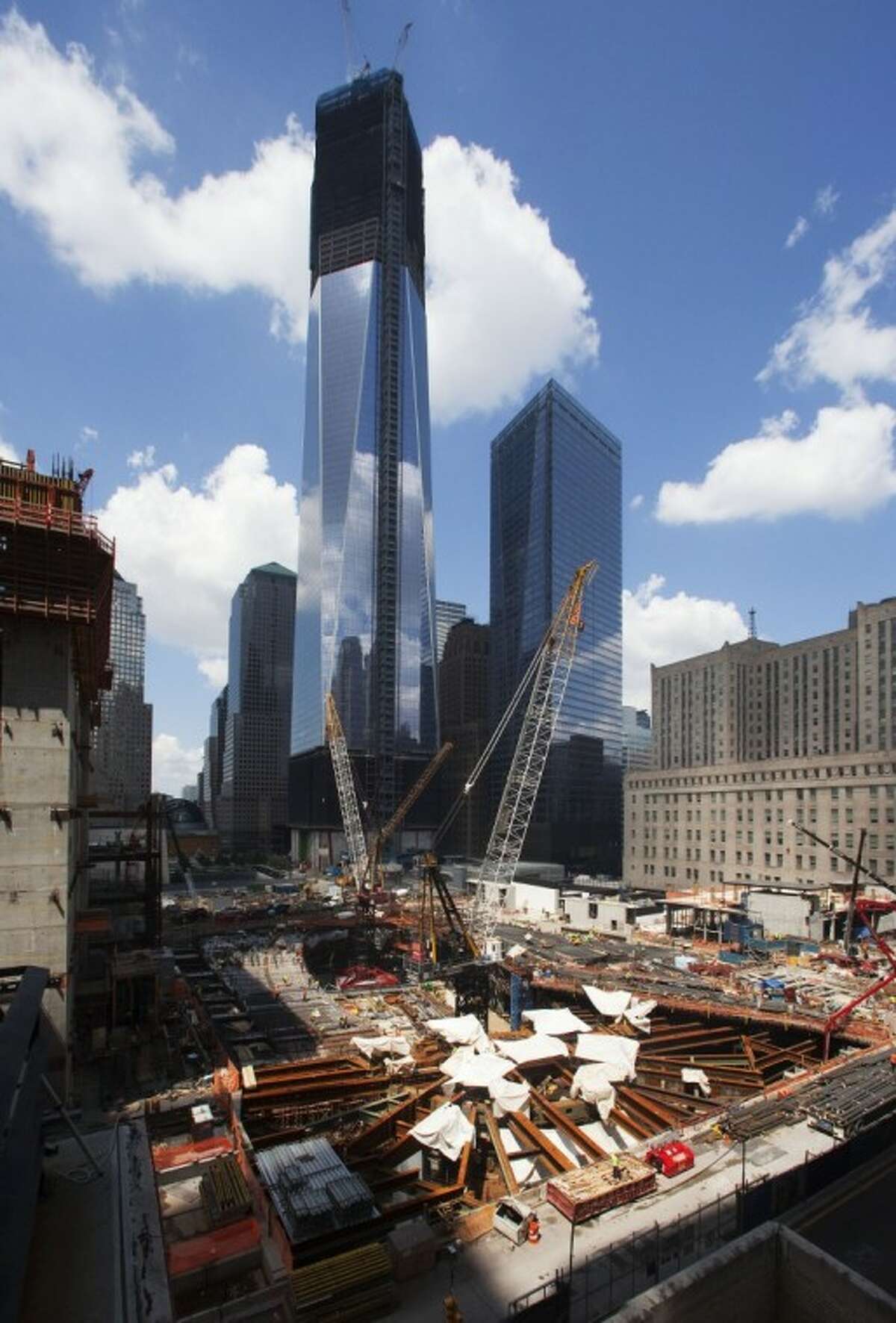 In this Aug. 16 photo, construction cranes work at the World Trade Center transportation hub in New York. One World Trade Center, top, now up to 104 floors, is slated for completion in 2014.