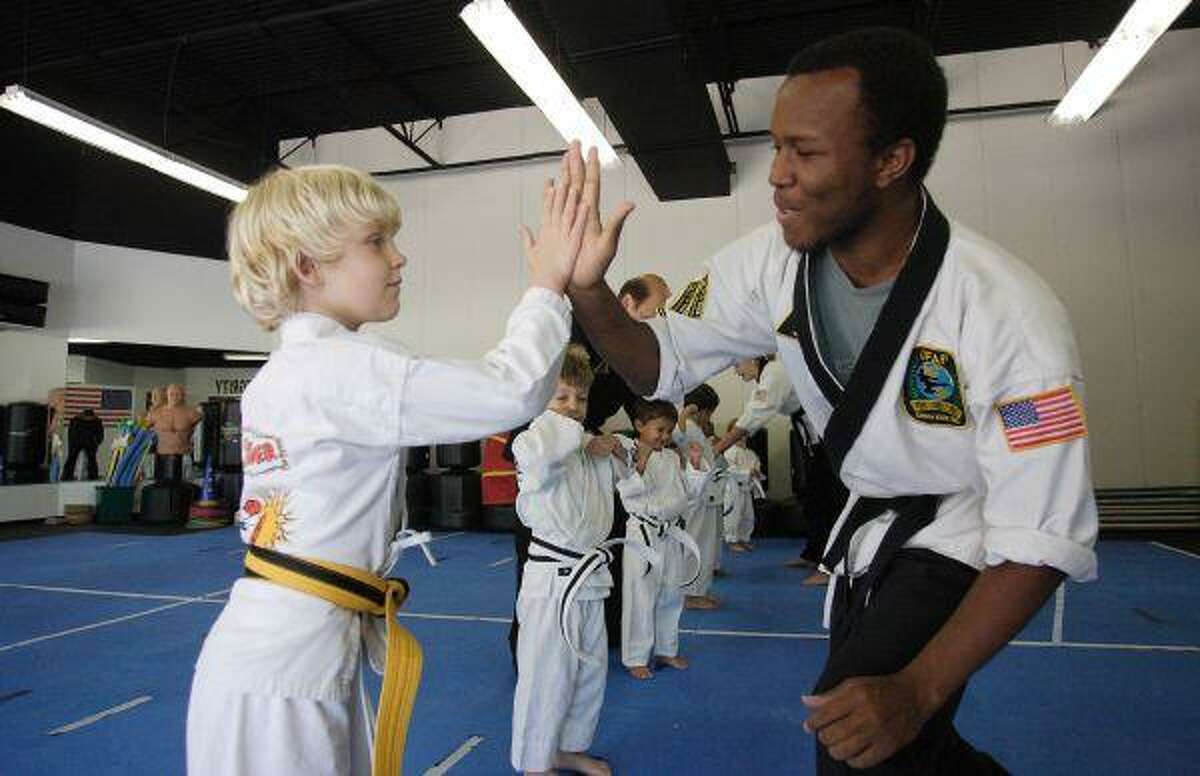 Jack Mischke, a student in Karate of The Woodlands, gives a high-five to instructor Damien Sauceda, a third-degree black belt, during the school’s “Tiger Tot” class Thursday. The school, owned by eighth-degree black belt Rick Prieto, has more than 400 students enrolled and is among the most popular in The Woodlands.