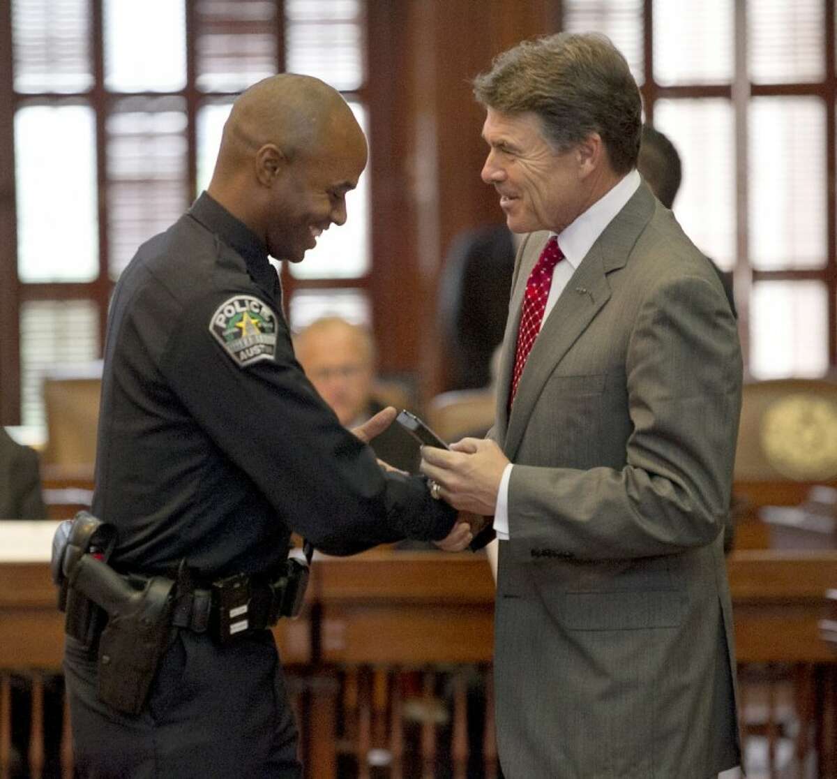 Texas Gov. Rick Perry presents seriously injured Austin Police officer Frank Wilson V with his medal after Perry gave remarks and presented the 2012 Star of Texas Awards, during a ceremony in the House Chambers in Austin on Sept. 14.