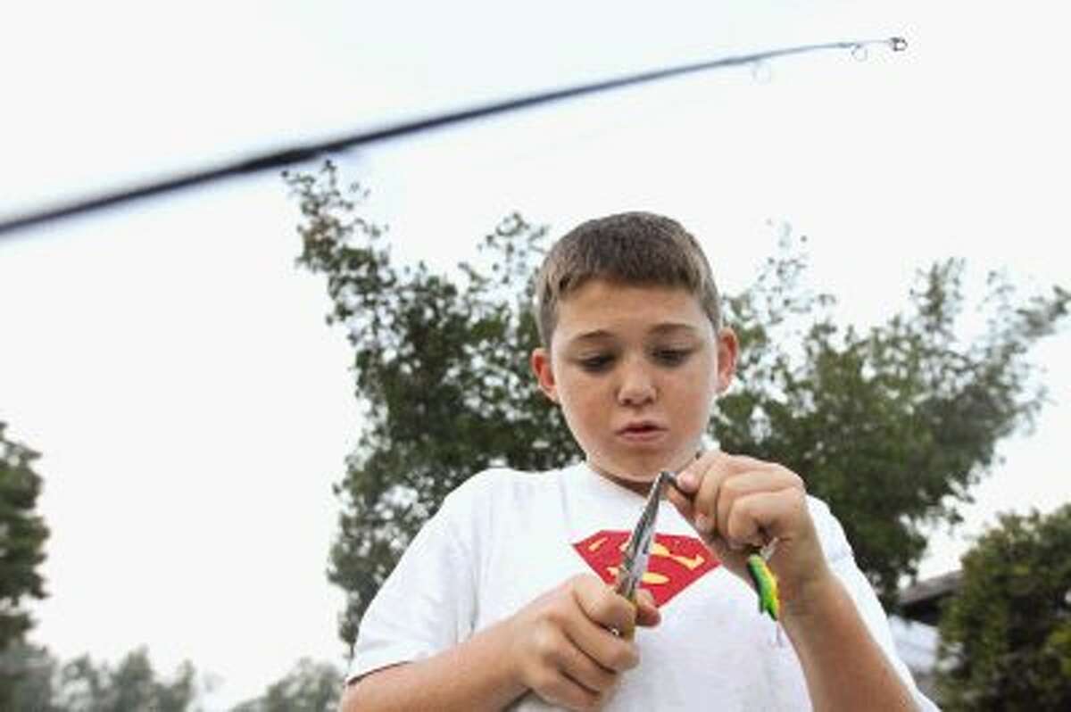 Payton Attaway prepares a lure during The Woodlands Kiwanis Club’s annual Kids’ Fishing Classic at Creekwood Park Saturday. Go to HCNPics.com to view and purchase this photo and others like it.