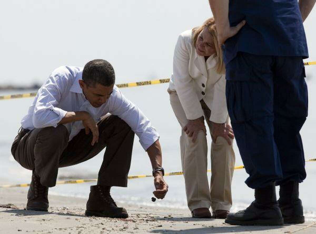 In this May 28, file photo, President Barack Obama picks up a “tar ball” as LaFourche Parish president Charlotte Randolph, center, and U.S. Coast Guard Admiral Thad Allen, National Incident Commander for the BP Deepwater Horizon oil spill, look on during a tour of areas impacted by the Gulf Coast oil spill in Port Fourchon, La.
