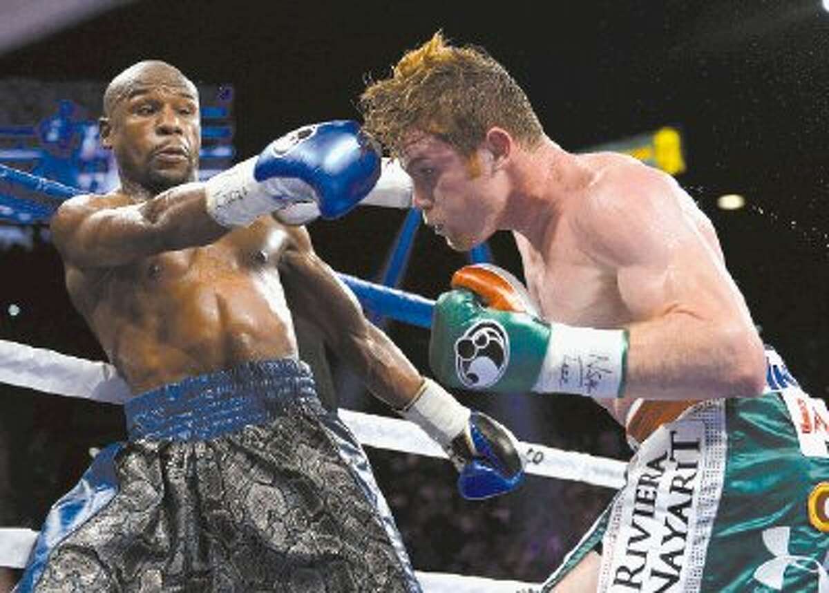 Canelo Alvarez, right, throws a jab at Floyd Mayweather Jr. in the fifth round during a 152-pound title fight, Saturday, in Las Vegas.