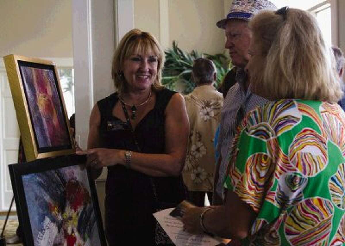 Rozi Turnbull shows her work to Rick and Margaret Mattix during the Bentwater’s Fine Art Festival. The Bentwater Yacht and Country Club and the Conroe Art League hosted the event Sunday at the Bentwater Yacht Club in Montgomery. Go to HCNPics.com to view and purchase this photo, and others like it.