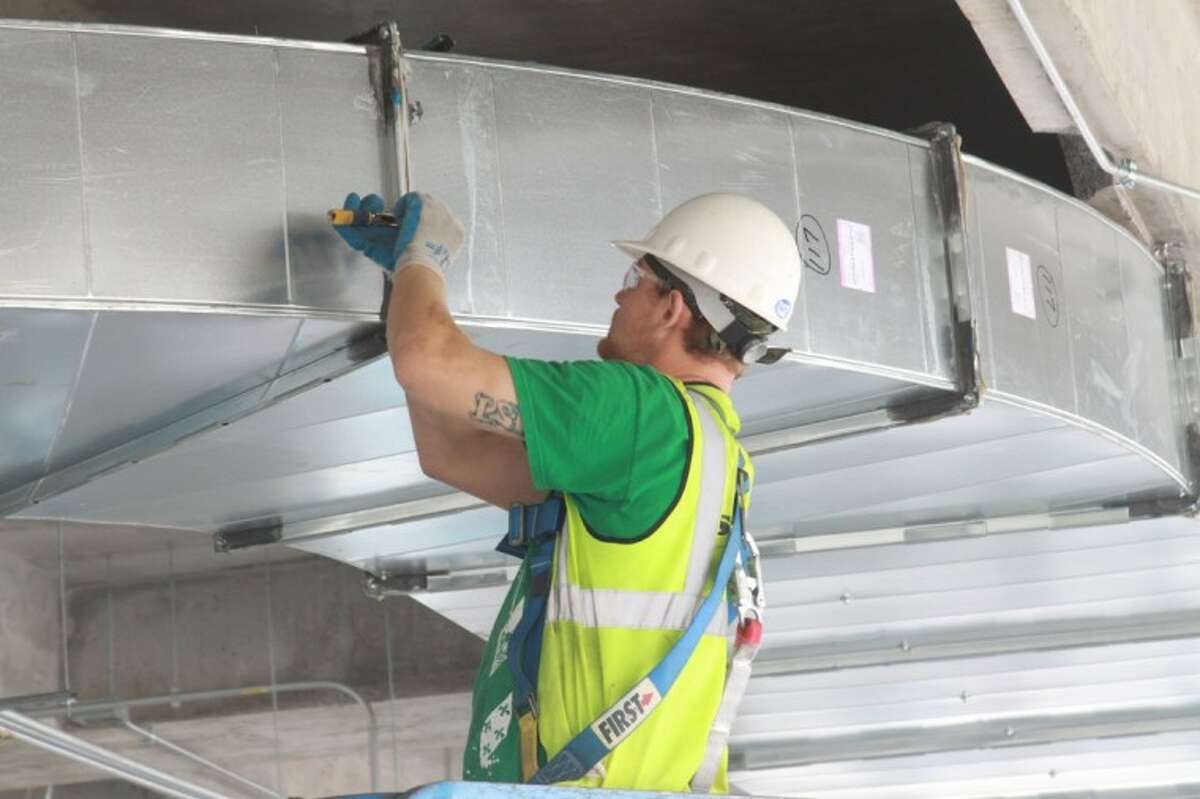 A worker installs some of the ductwork for air conditioning for Building 4 at Research Forest Lakeside.
