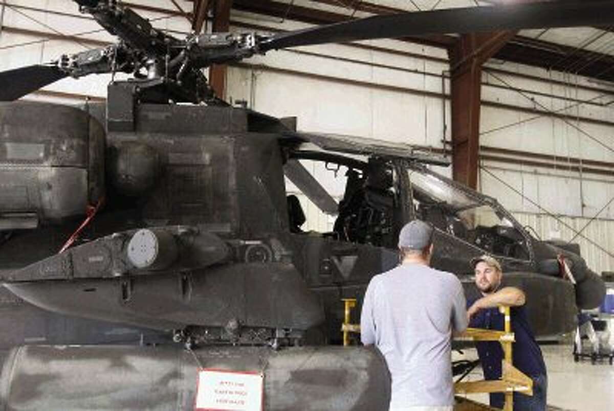 Civilian contract workers, who assist the military staff in maintaining Apache helicopters, talk at the United States Army Reserve Aviation Support Facility Tuesday in Conroe. The government shutdown put the 56 military staff on furlough along with the rest of the 72 other military personnel. The civilian crew will shoulder additional maintenance responsibilities while the military members are on furlough.