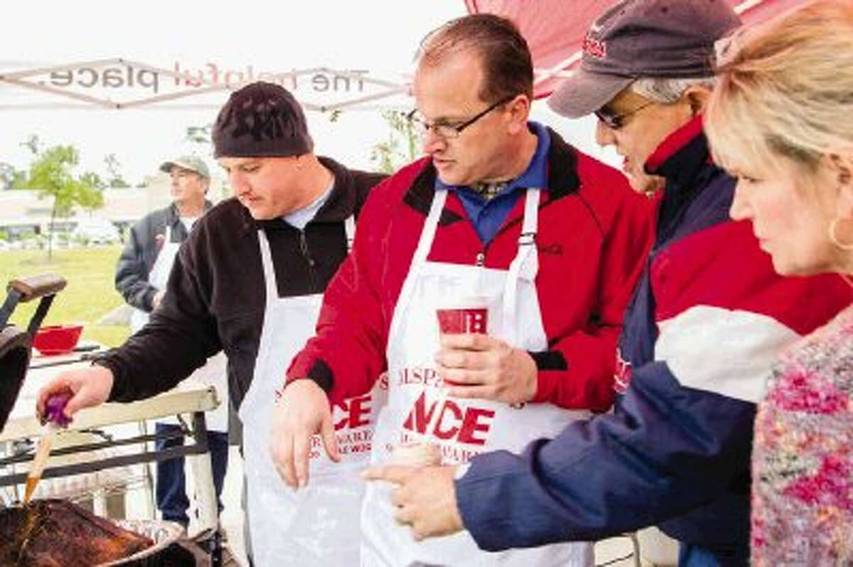 Alspaugh’s Ace Hardware of The Woodlands Assistant Manager Nick Davis bastes a turkey while the General Manager Troy Blackmon shows Lisa and Gerry Nemeth a grill during Turkey Fry Day, a cooking demonstrating event featuring various grills on Sunday.
