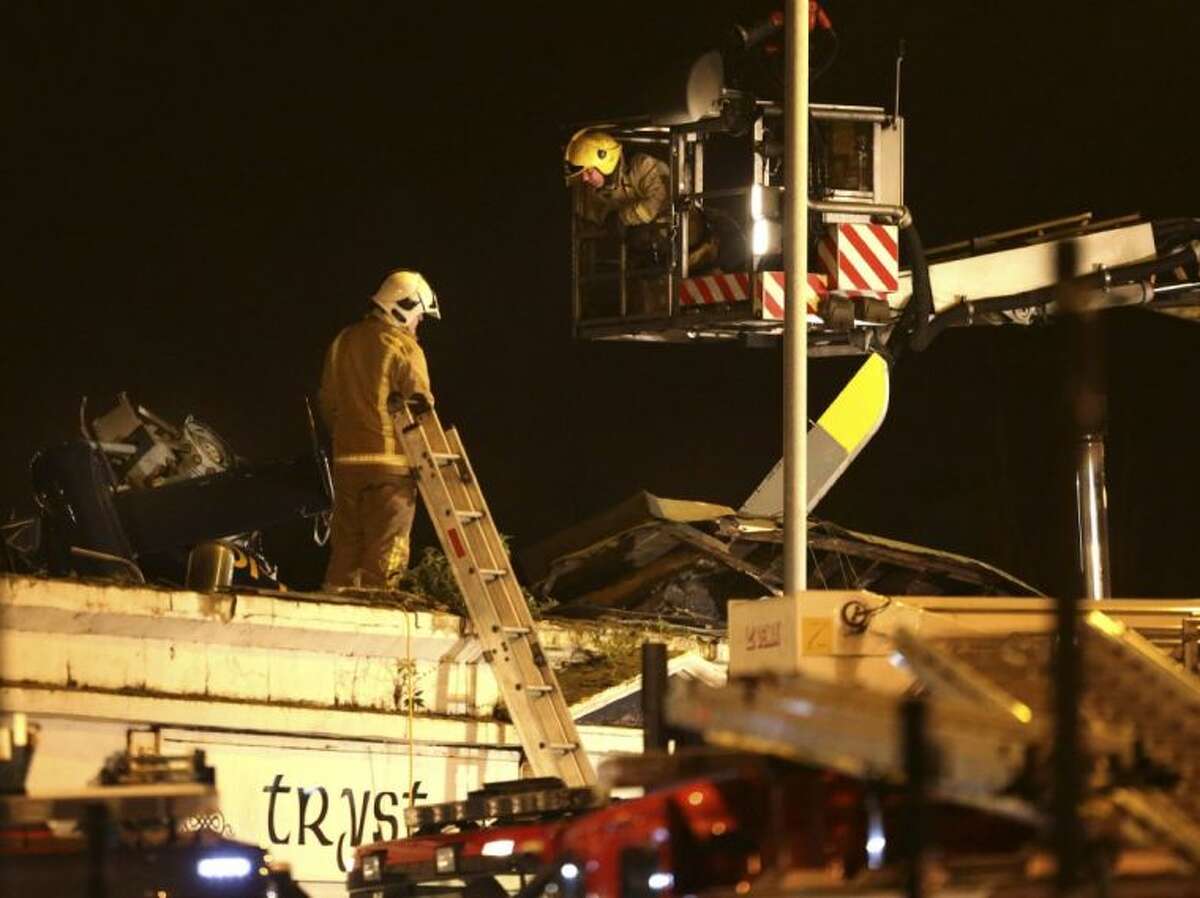 Firefighters inspect the damage at the site of a helicopter crash in Glasgow early Saturday. The police helicopter crashed late Friday night into the roof of a popular pub in Glasgow, Scotland.