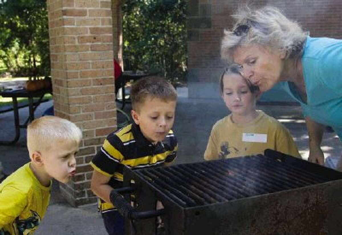 Gayle Fisher helps start a fire with Waylan and Nolan Aune and Aidan Rivers during the Special Needs Sibling meet-up Sunday at the Alden Bridge Park Pavilion in The Woodlands. Go to HCNPics.com to view and purchase this photo and others like it.