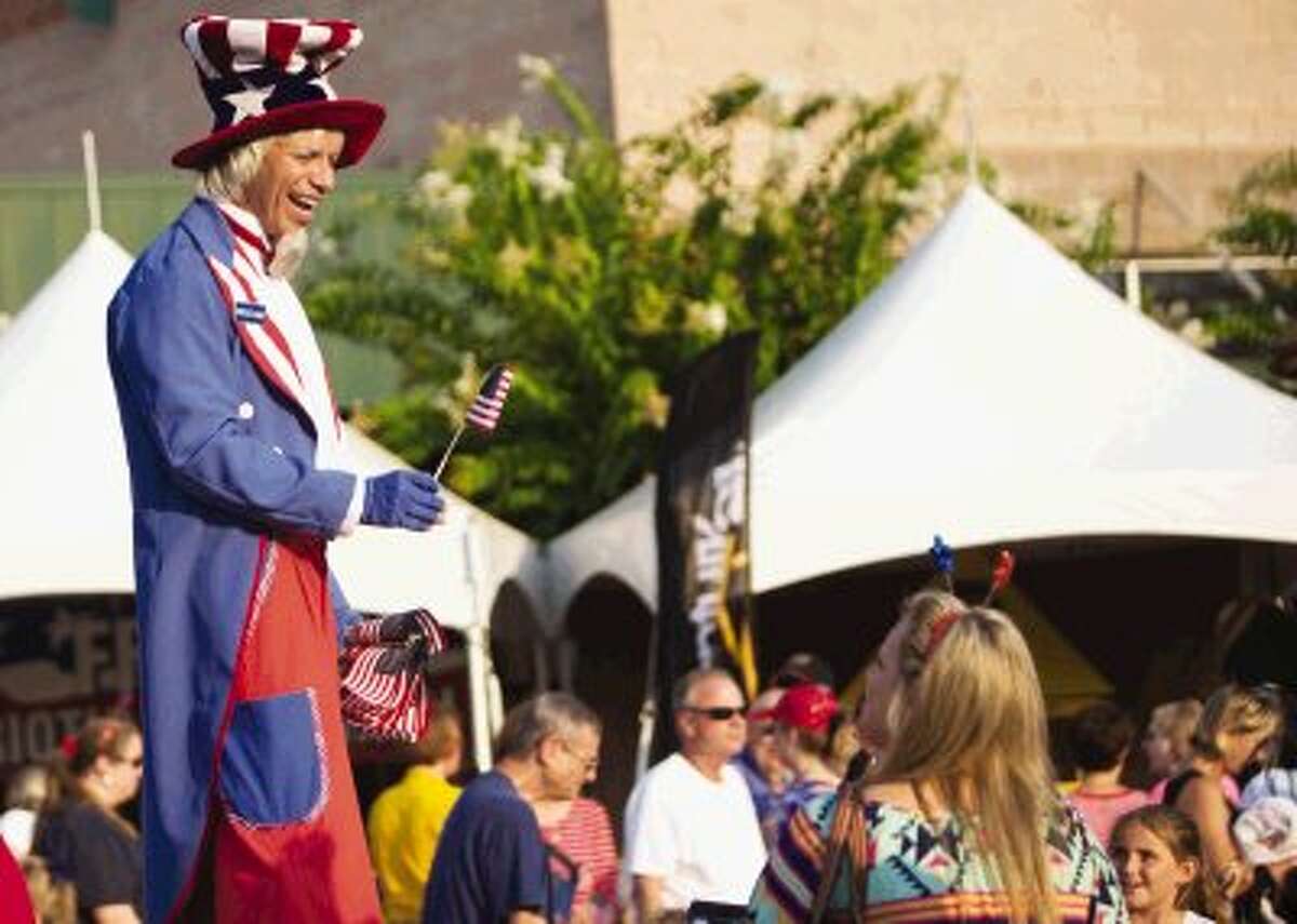 A man dressed as Uncle Sam distributes free flags to concert goers during Wednesday’s annual Star Spangled Salute with the Houston Symphony at The Cynthia Woods Mitchell Pavilion in The Woodlands. To view or order this photo and others like it, visit HCNPics.com.