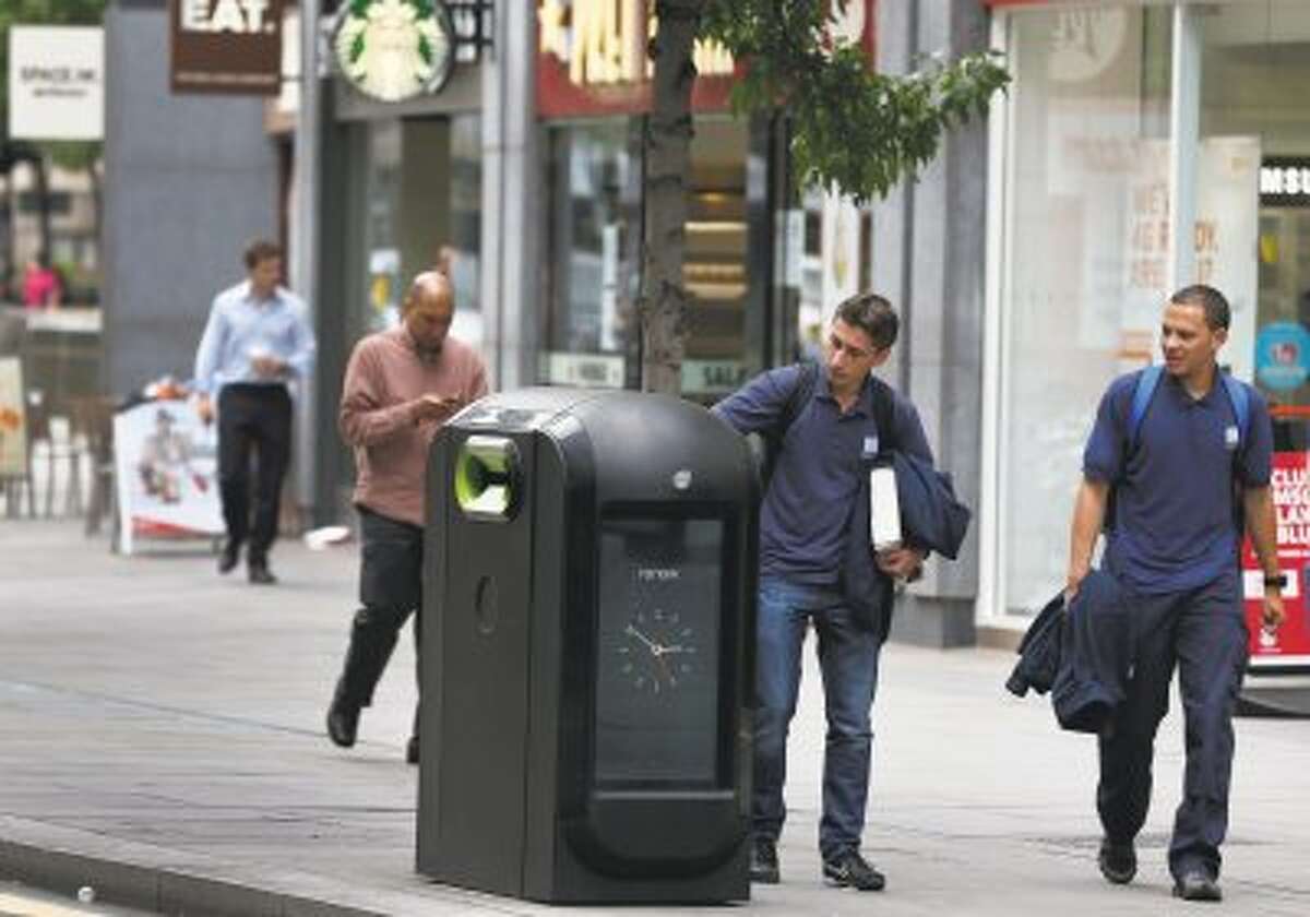 A man uses a trash bin in central London, Monday, Aug. 12, 2013. Officials say that an advertising firm must immediately stop using its network of high-tech trash cans, like this one, to track people walking through London's financial district. The City of London Corporation says it has demanded Renew pull the plug on the program, which measures the Wi-Fi signals emitted by smartphones to follow commuters as they pass the garbage cans.