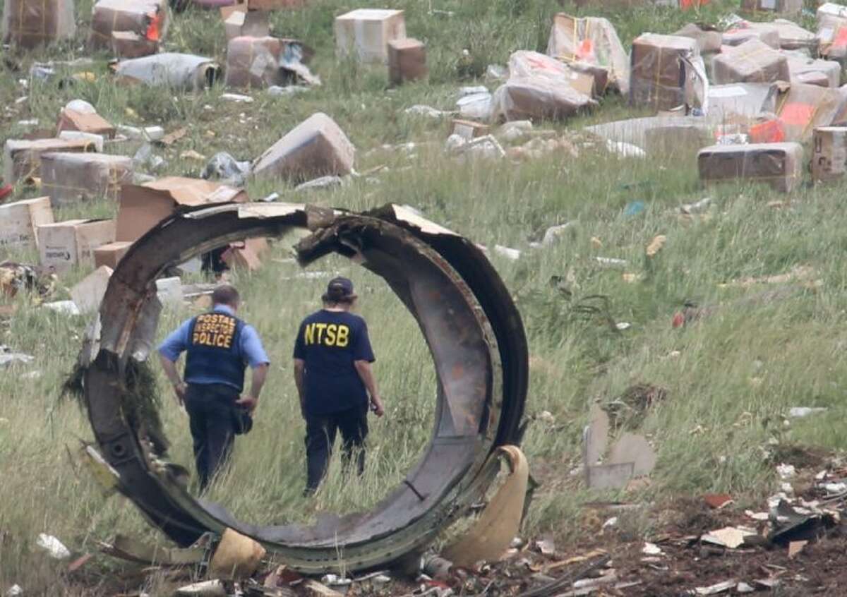 A postal Inspector officer and a NTSB investigator are seen through a section debris of a UPS A300 cargo plane after it crashed on approach at Birmingham-Shuttlesworth International Airport Wednesday.