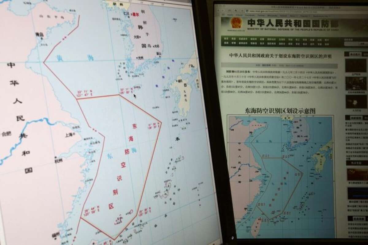Computer screens display a map showing the outline of China’s new air defense zone in the East China on the website of the Chinese Ministry of Defense, in Beijing Tuesday. On Saturday Beijing issued a map of the zone — which includes a cluster of islands controlled by Japan but also claimed by China — and a set of rules that say all aircraft entering the area must notify Chinese authorities and are subject to emergency military measures if they do not identify themselves or obey Beijing’s orders. Chinese characters in red in the center of the map at left reads: “Air Defense Identification Zone in East China Sea.”