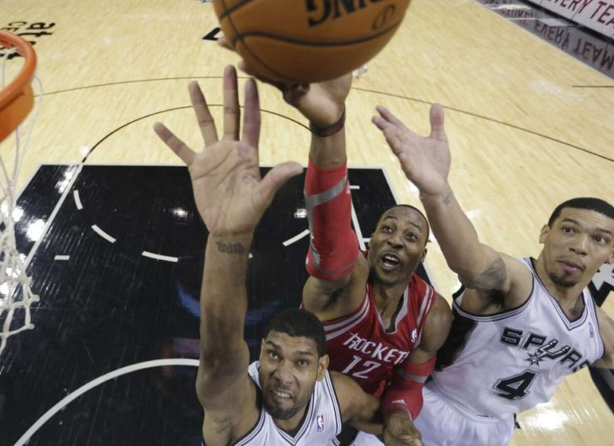 Houston Rockets center Dwight Howard shoots over the San Antonio Spurs’ Tim Duncan, left, and Danny Green during the first half of a preseason game Thursday in San Antonio.