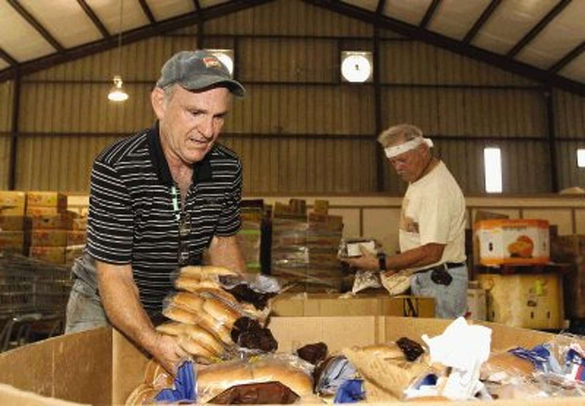 Volunteers Gerald Myers and Kevin Hare sort food into baskets at the MaTee’s Food Pantry at First Baptist Church in Groceville Wednesday.