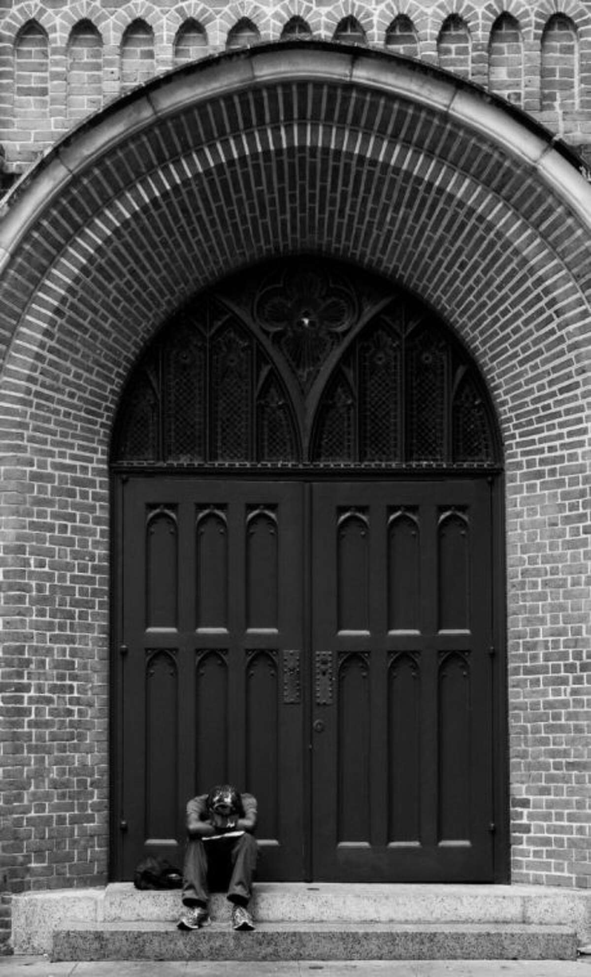 This black and white street photography was taken September 2013 at a church in downtown Houston by area resident Ansel Arnold of an anonymous man resting under a large brick archway.