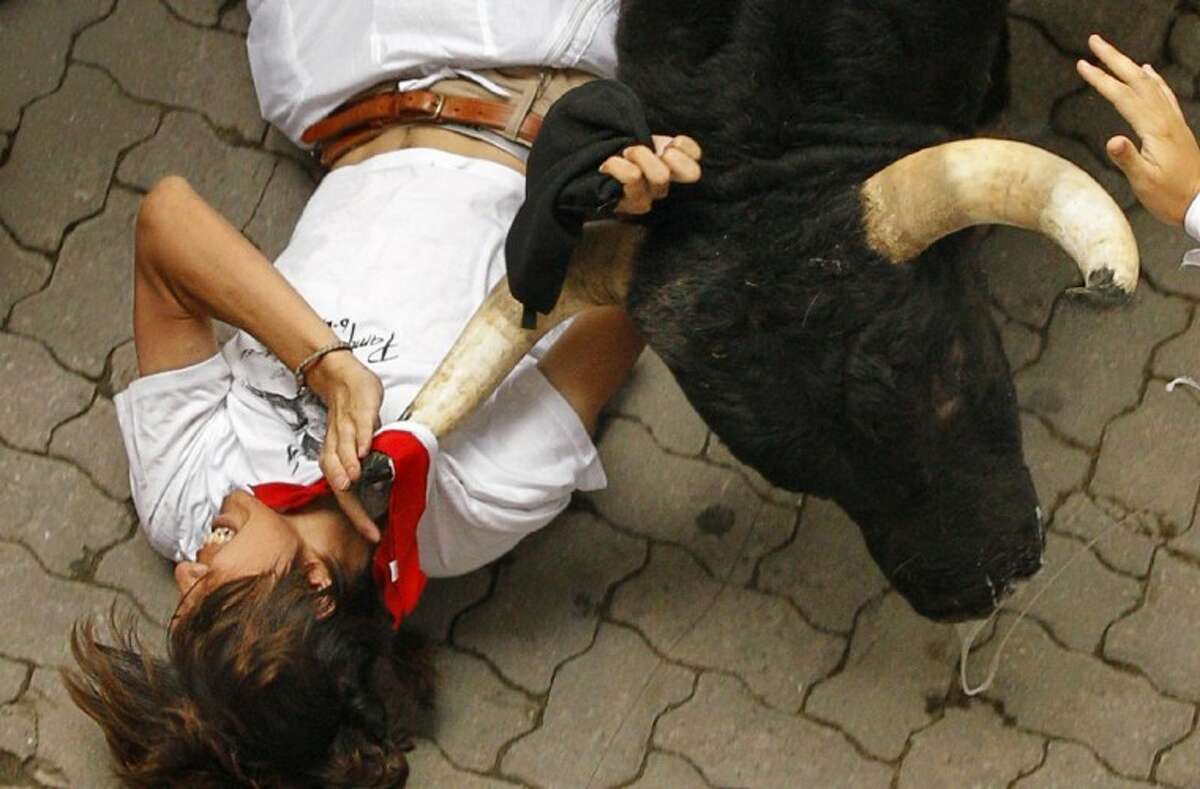 A reveler is tossed by a Dolores Aguirre Yabarra ranch fighting bull during the running of the bulls of the San Fermin festival, in Pamplona Spain, Saturday.