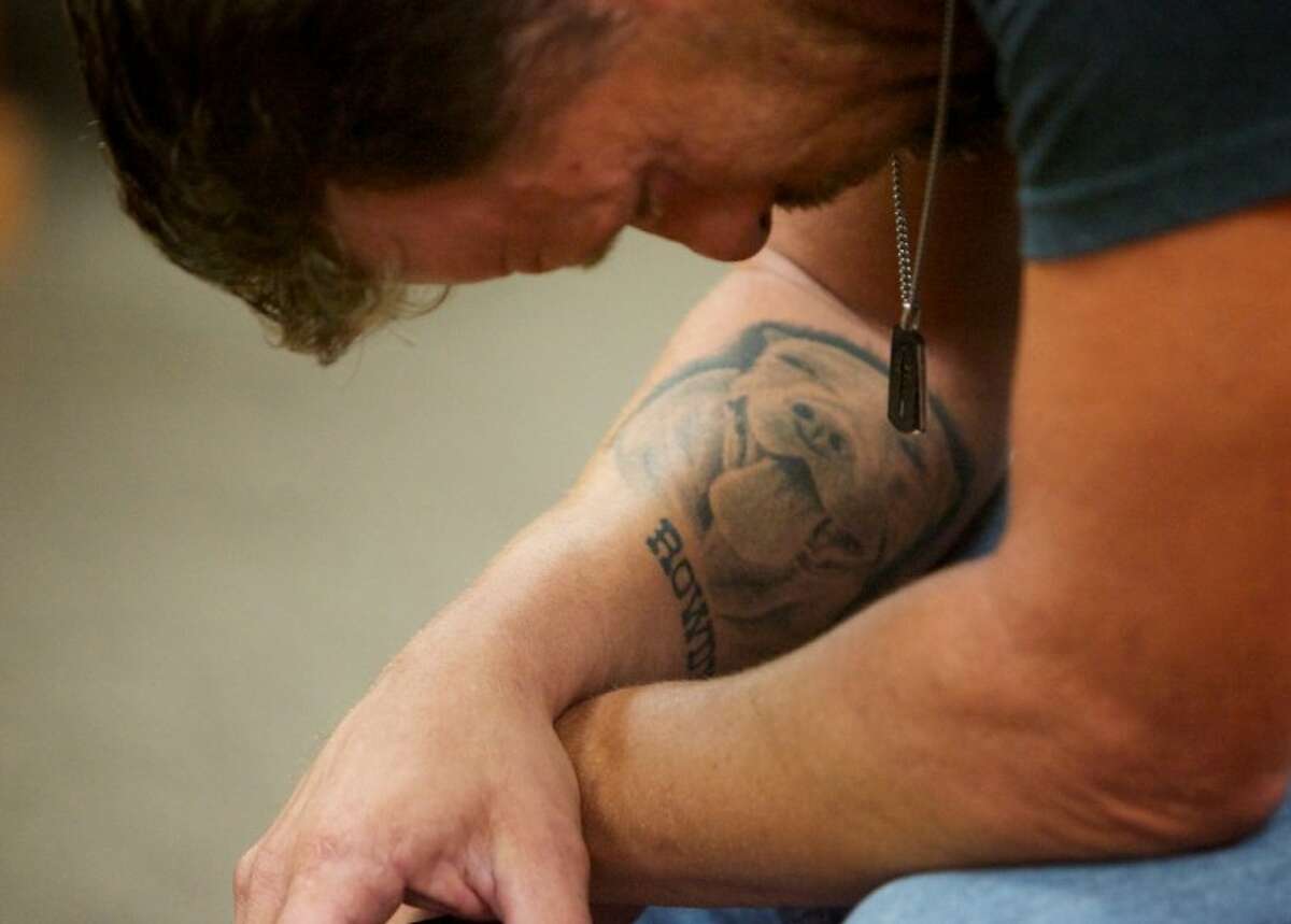 Scott Mulanski takes a moment to reflect as he hears about the condition of dogs seized from Spindletop. A tattoo of his dog “Rowdy” is seen on his forearm.