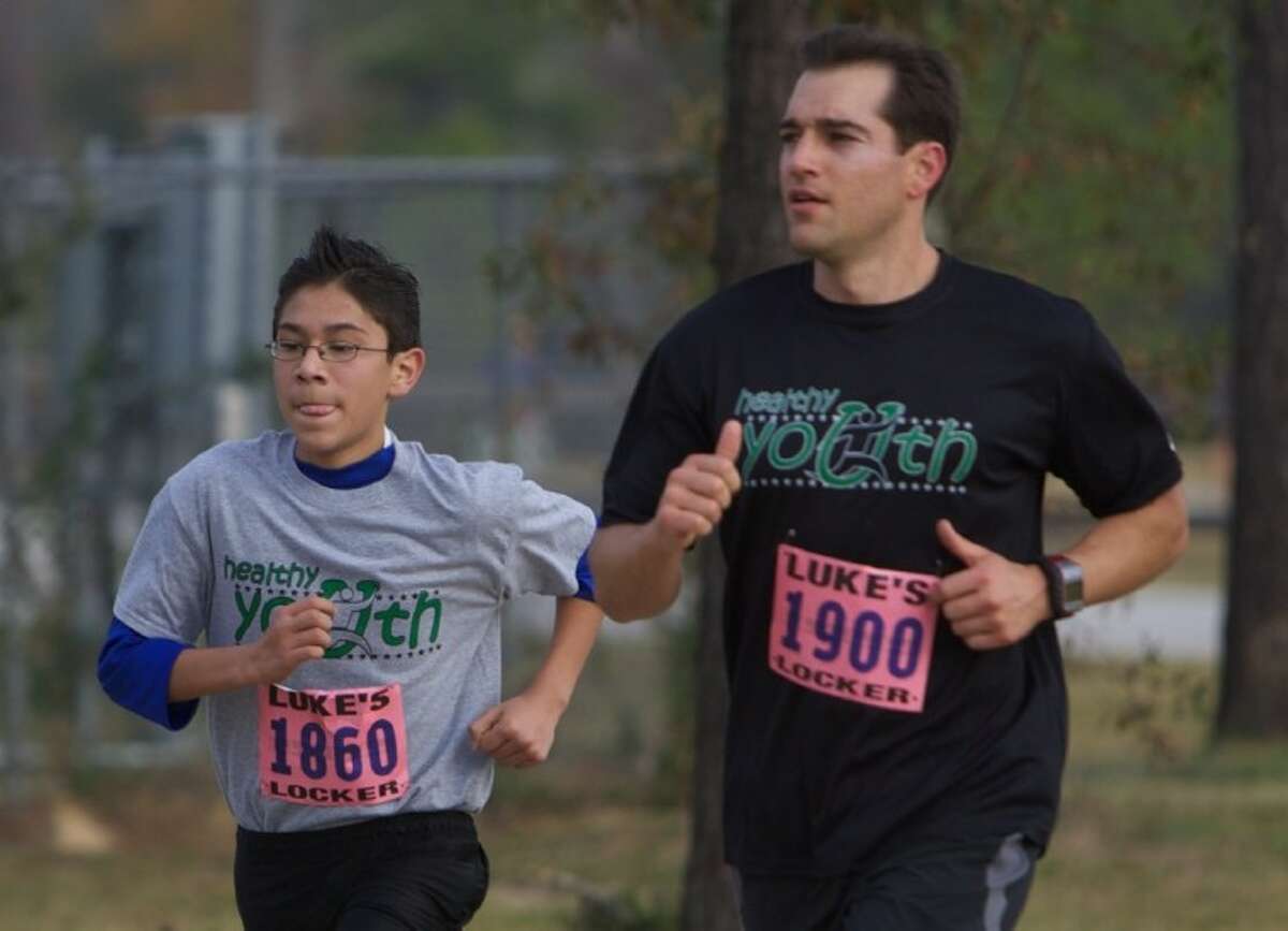 Eduardo Linares, 13, with the Healthy Youth program, runs alongside Matt Twombly, of The Woodlands, during the Eighth Annual Turkey Trot 5K Run at Carl Barton Jr. Park in Conroe Friday.